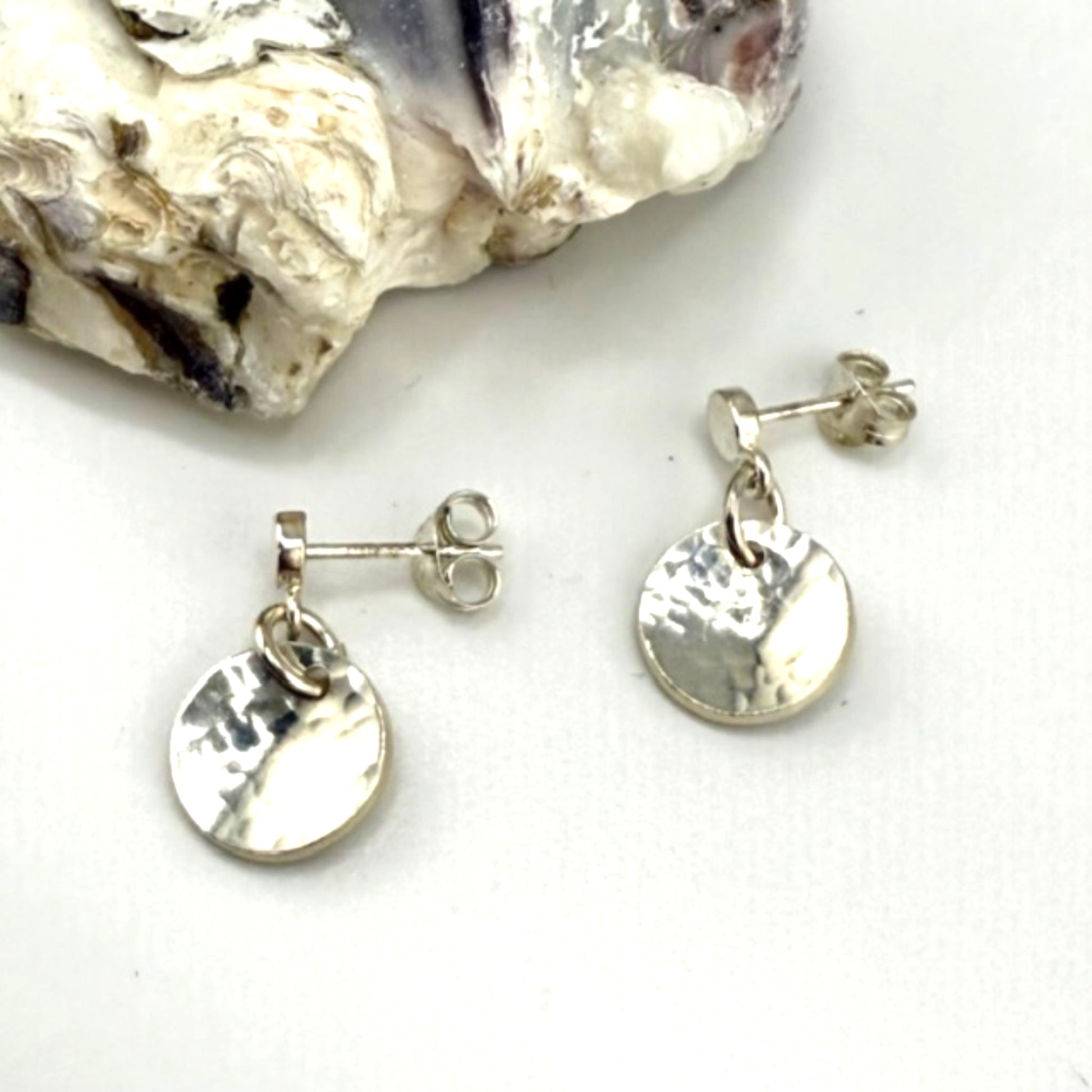 Silver disc earrings on a white surface
