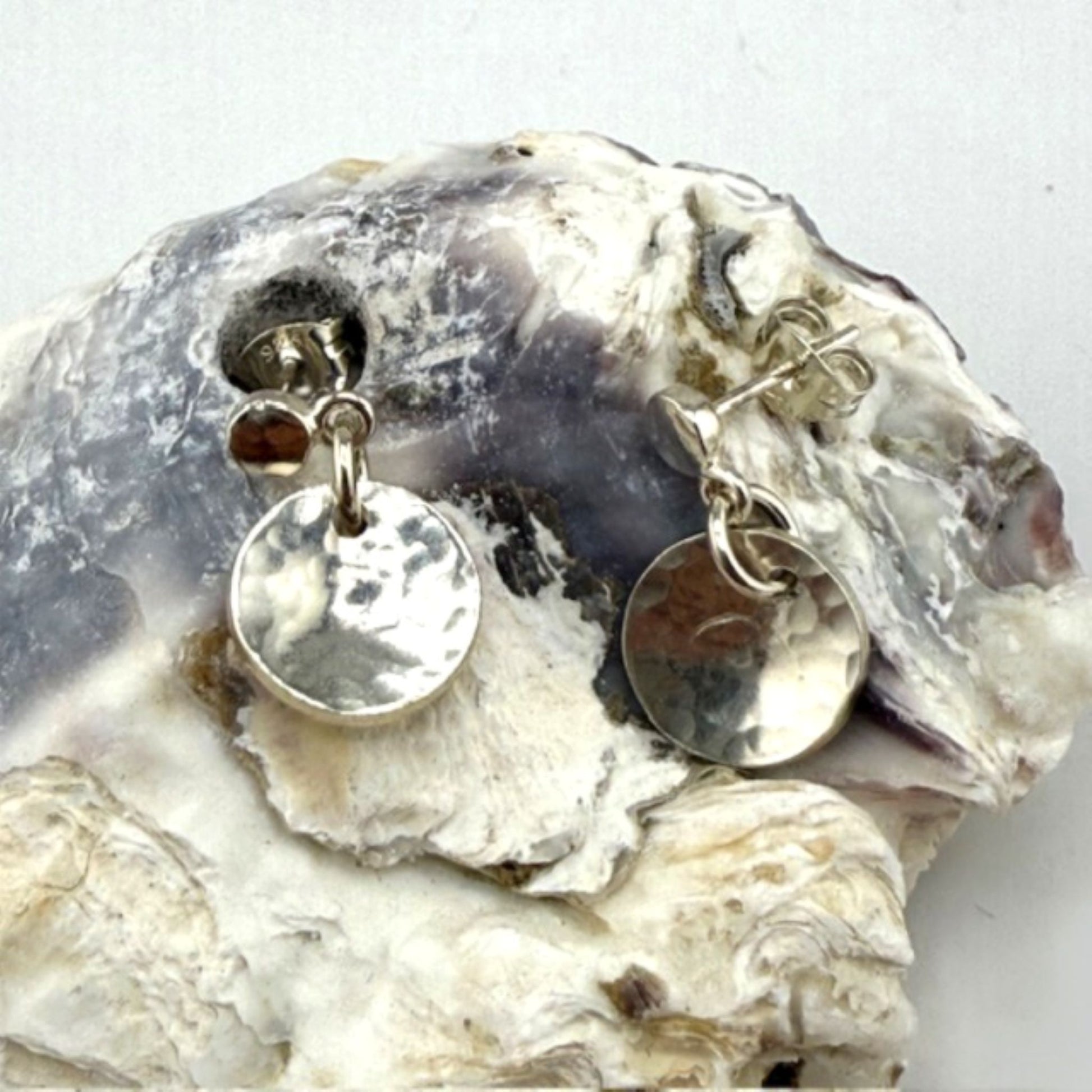 Silver earrings with round pendants on a shell background