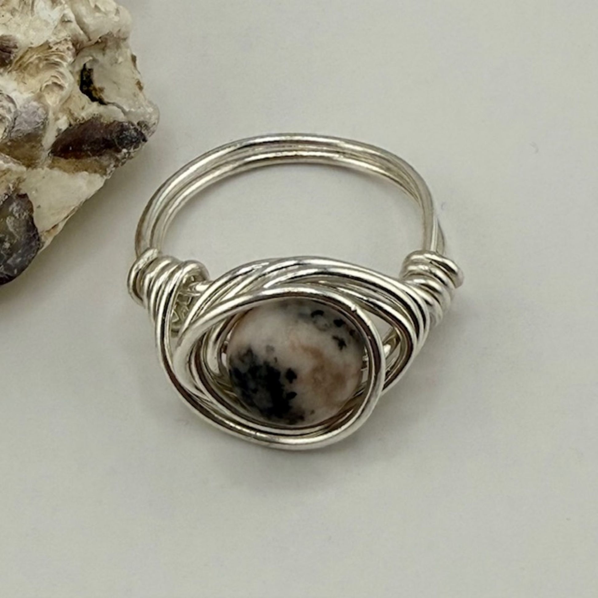 Silver ring with a gemstone on a light gray background