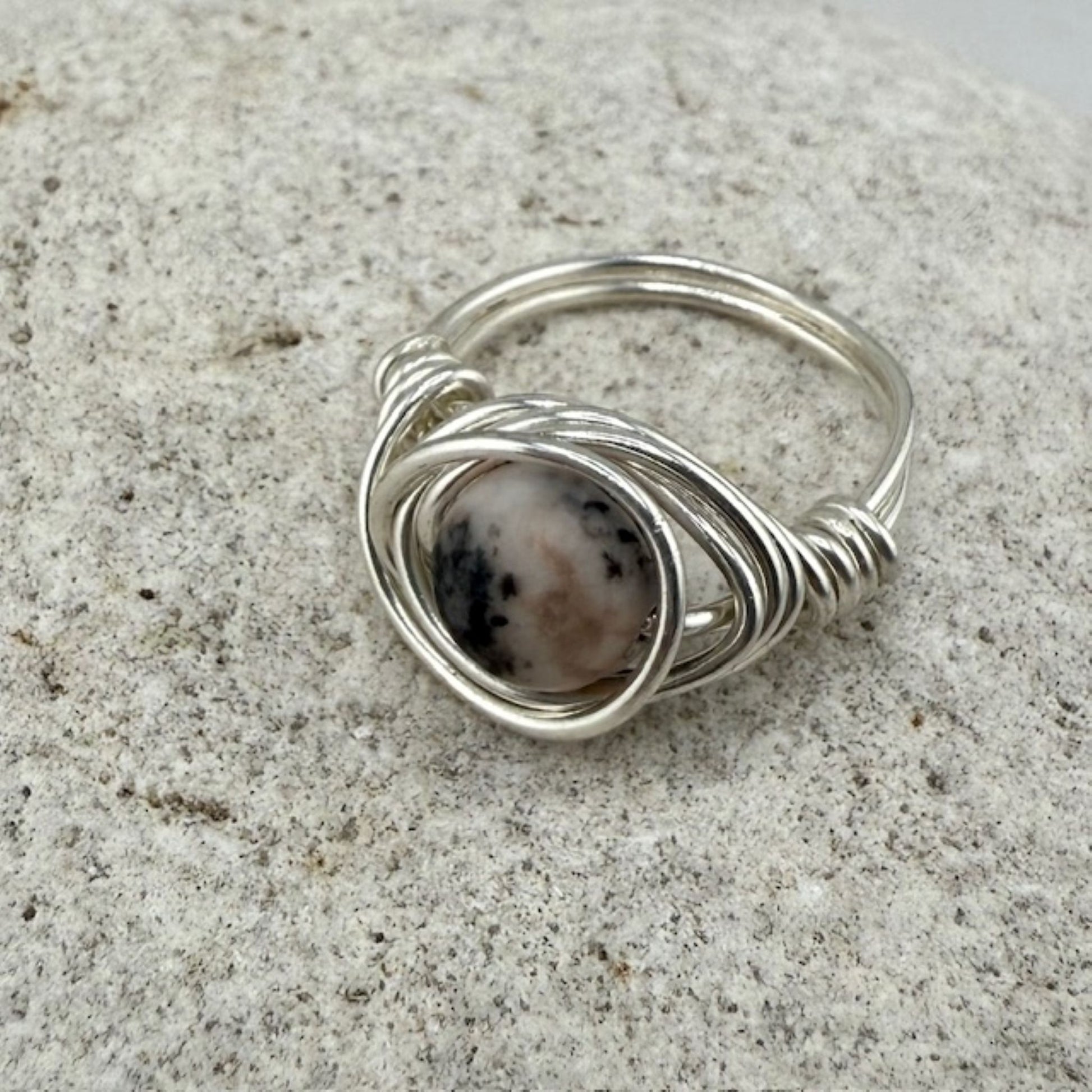 Silver wire-wrapped ring with a natural stone on a textured surface