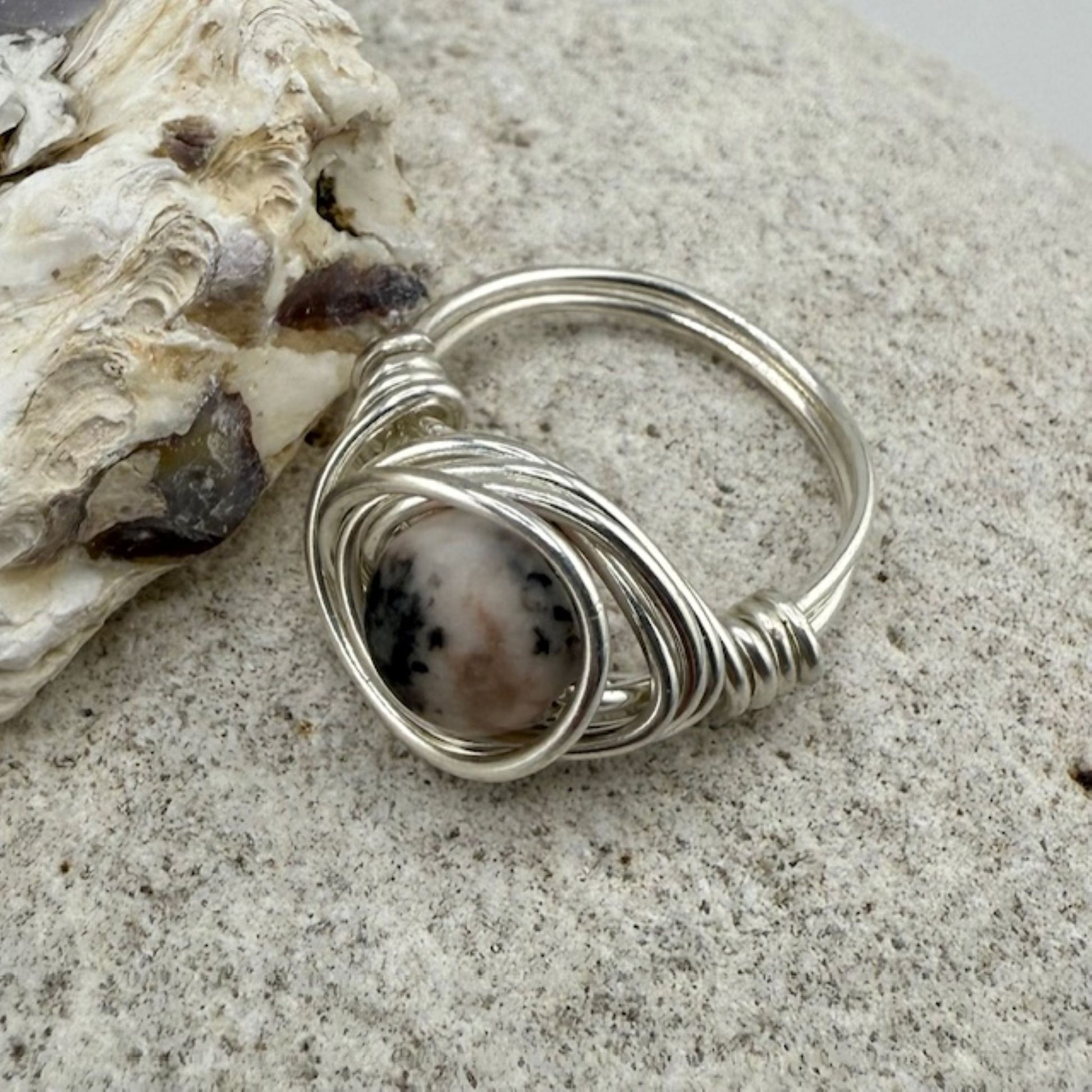 Silver ring with a pink jasper gemstone on a textured surface