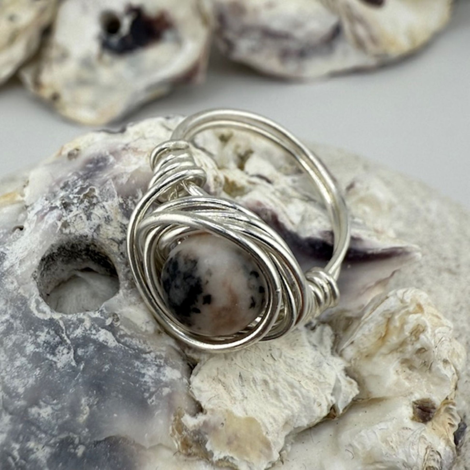 Silver wire-wrapped ring with a central stone on a textured stone surface