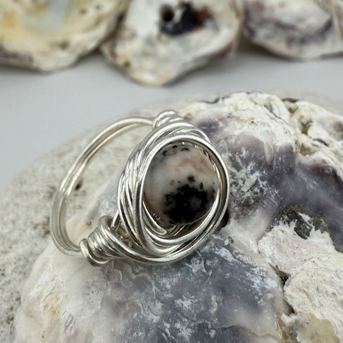 Silver wire-wrapped ring with a natural stone on a textured surface
