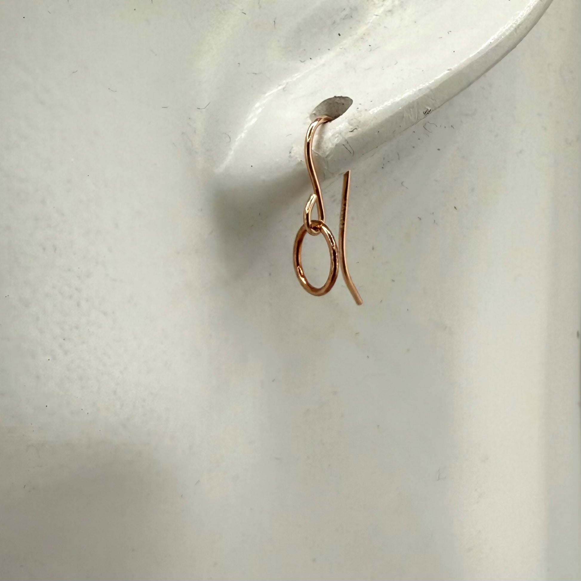 Rose gold circle hoop earring on a white ear display