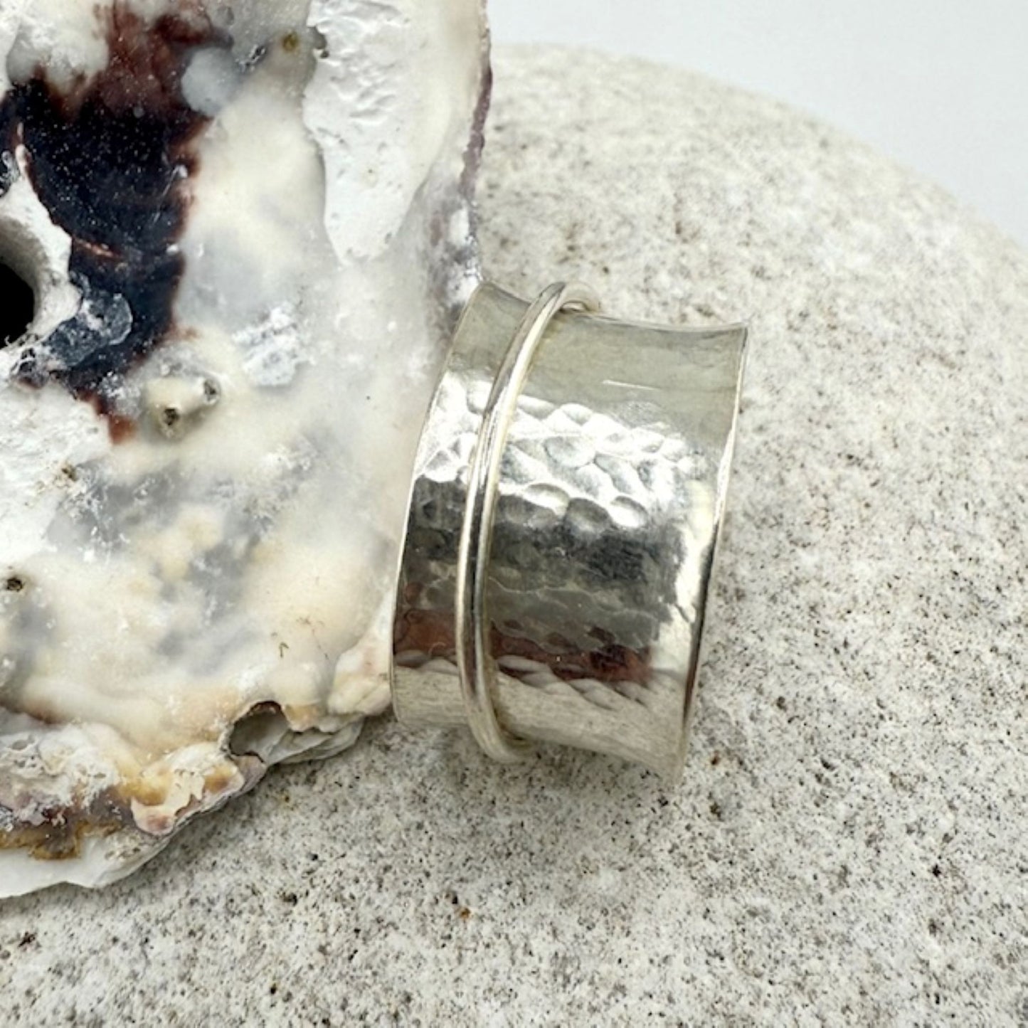 Silver spinner ring on a textured surface with a natural rock background