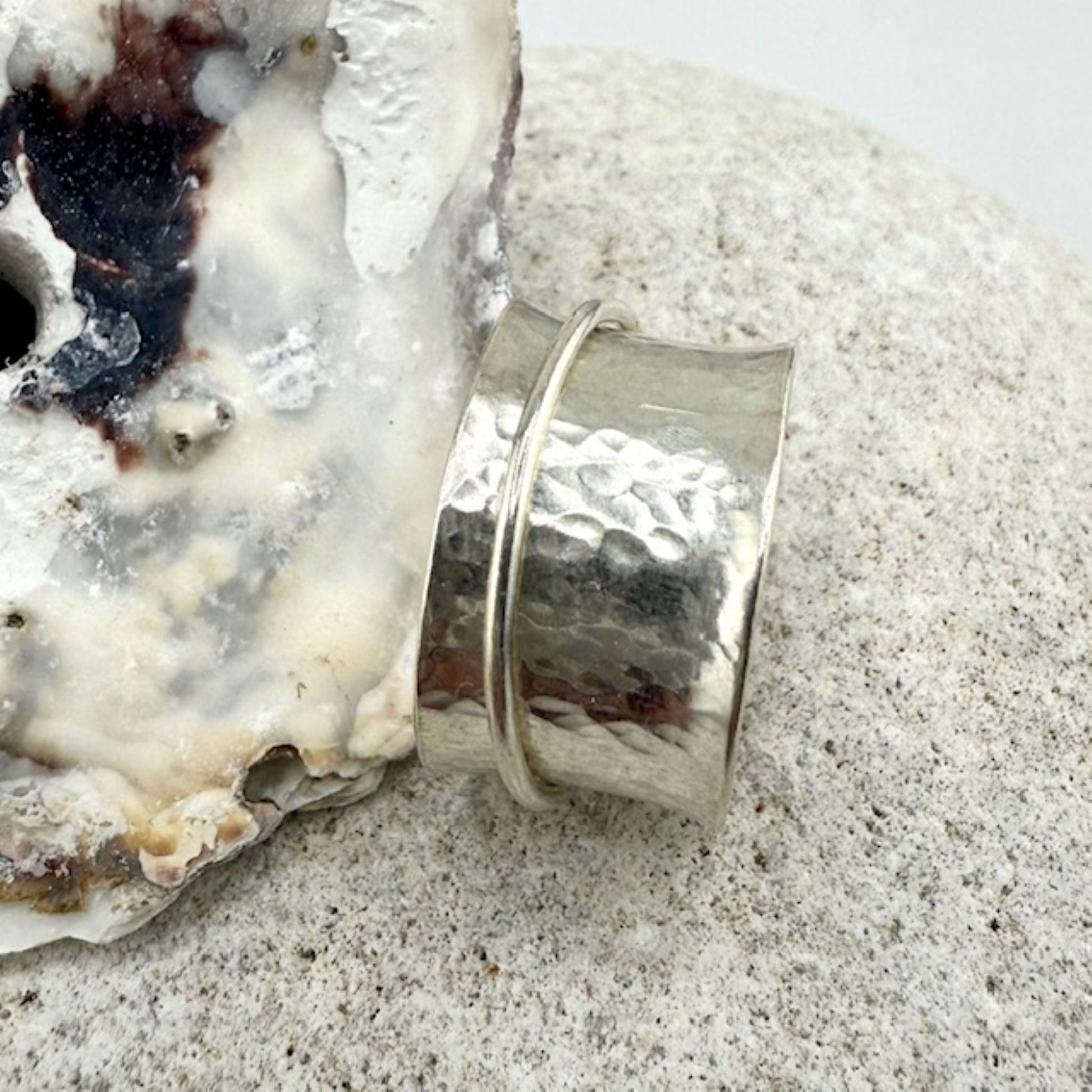 Silver spinner ring on a textured surface with a natural rock background