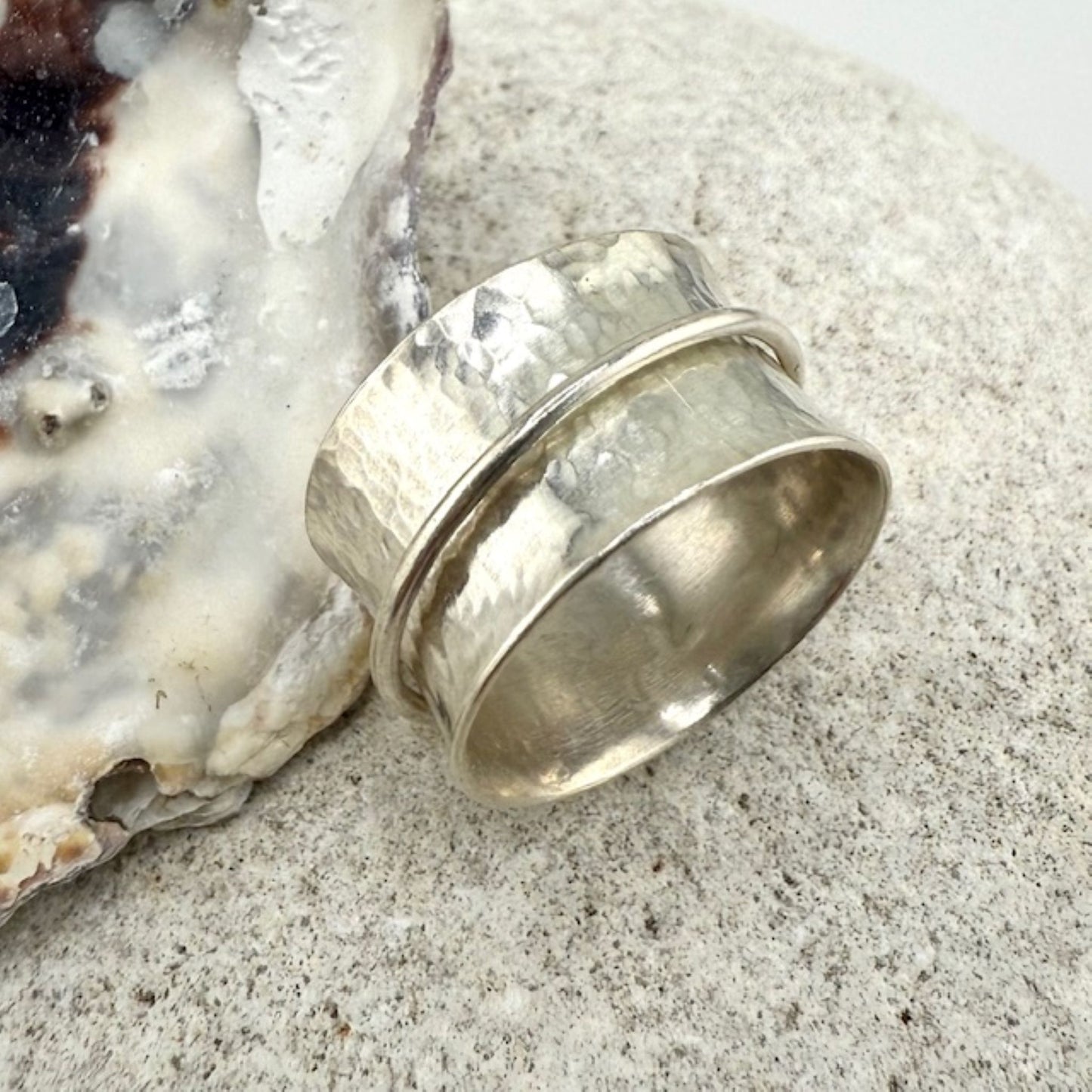 Silver spinner ring on a textured surface with an oyster shell