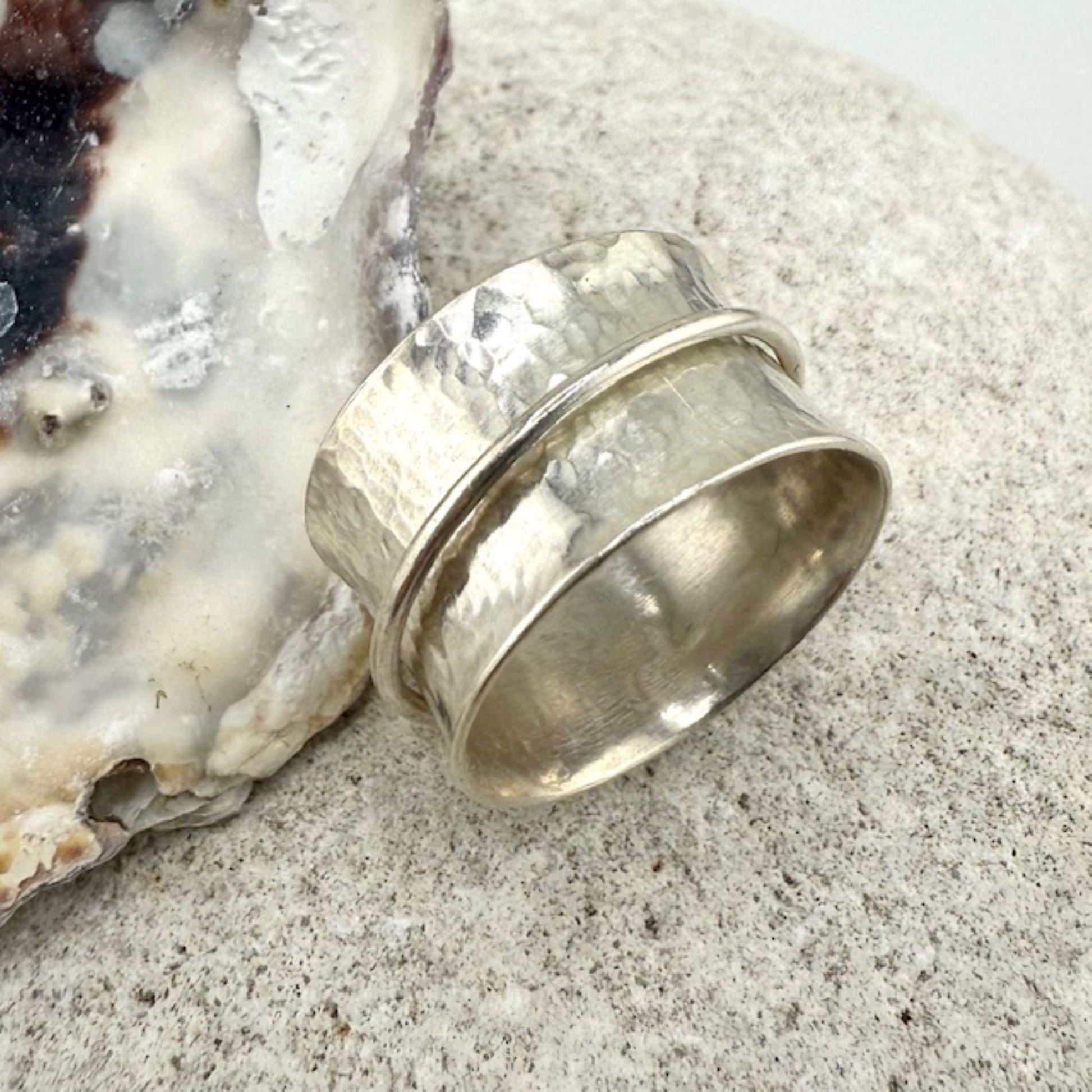Silver spinner ring on a textured surface with an oyster shell