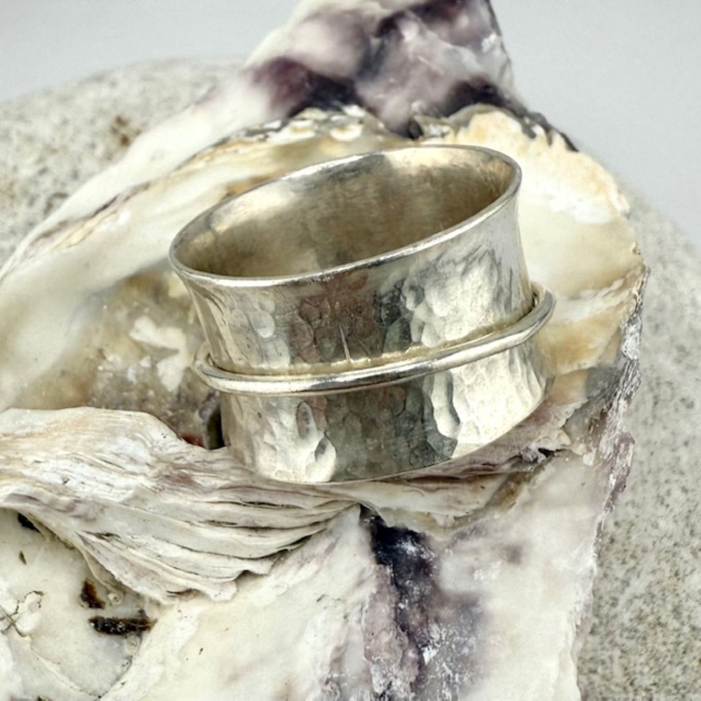 Silver spinner ring on a textured surface with a natural background