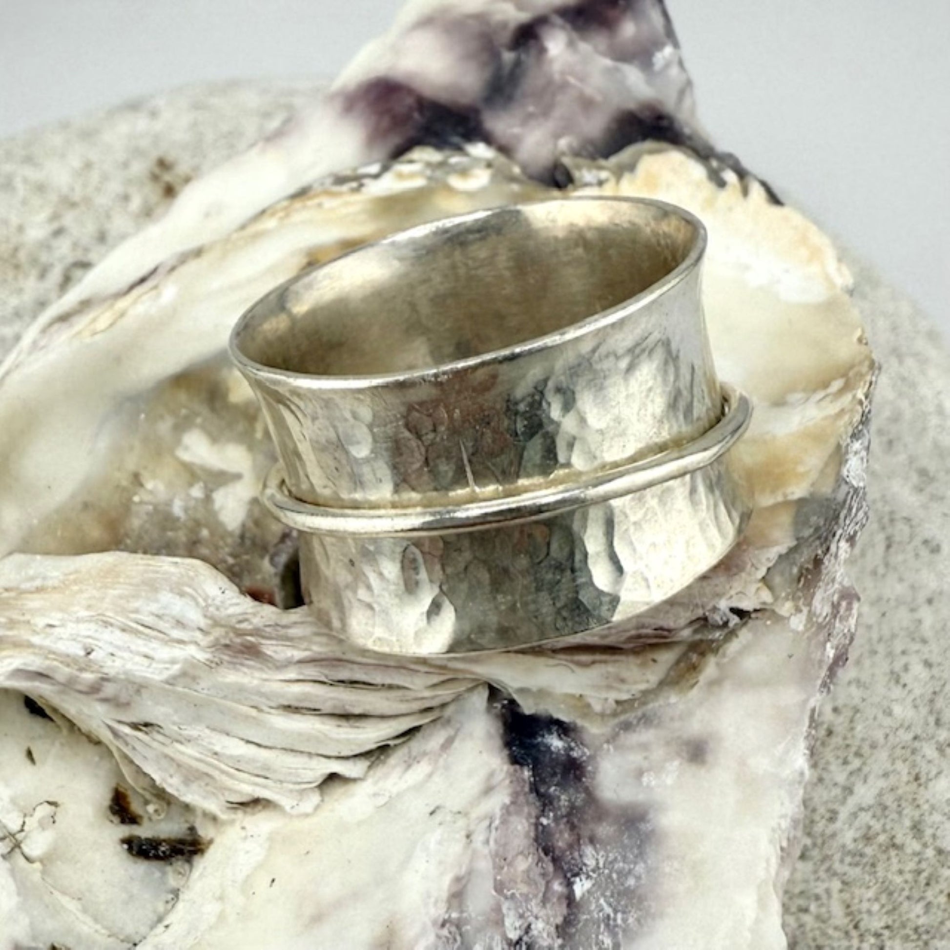 Silver spinner ring on a textured surface with a natural background