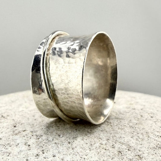 Silver spinner ring with a textured band on a gray surface