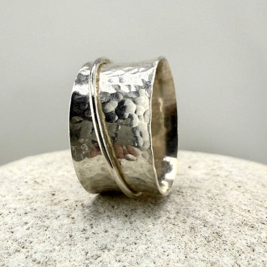 Silver spinner ring with a textured surface on a light gray background