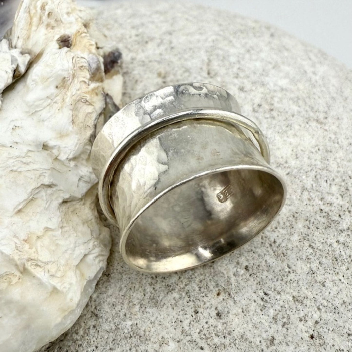 Silver spinner ring on a textured stone surface