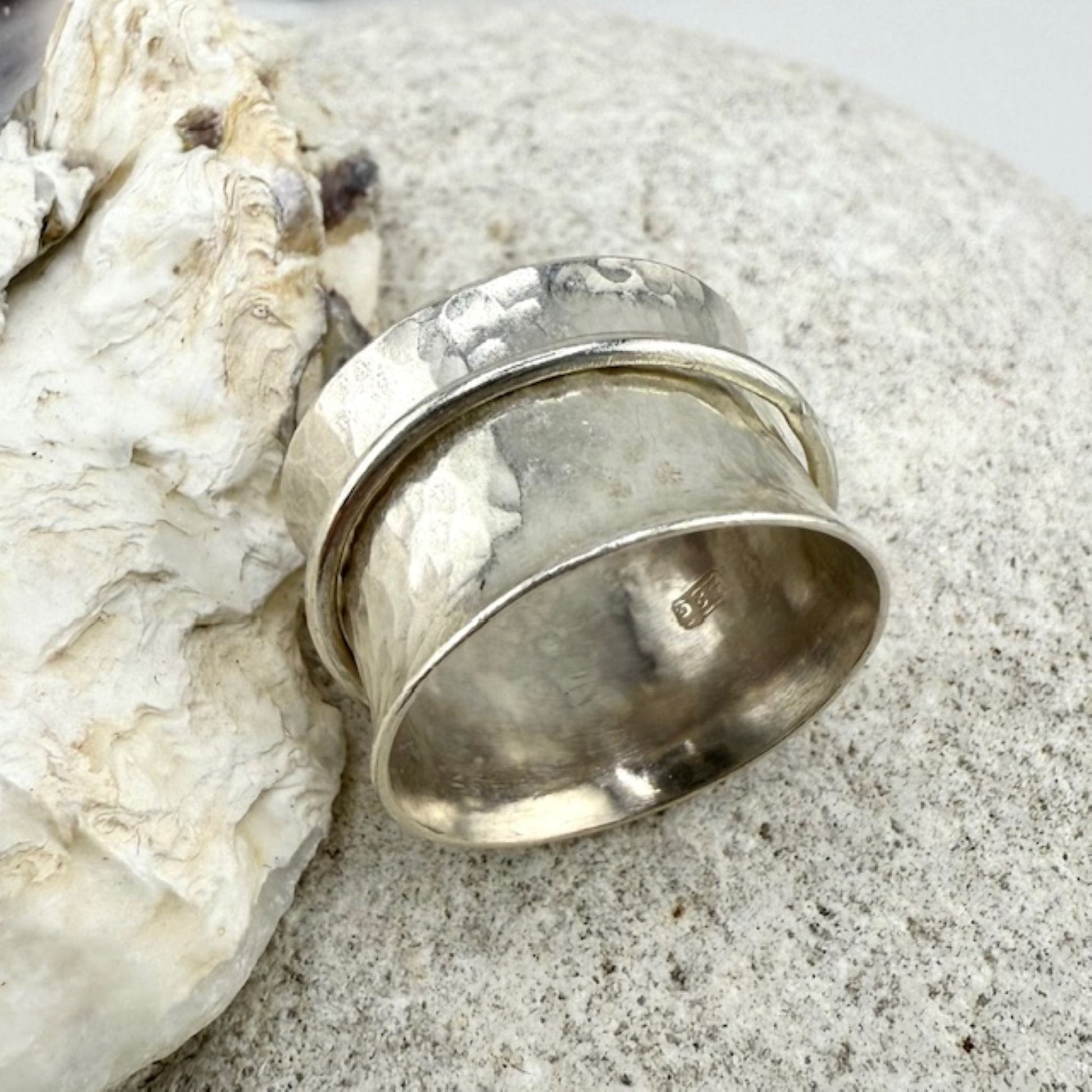 Silver spinner ring on a textured stone surface