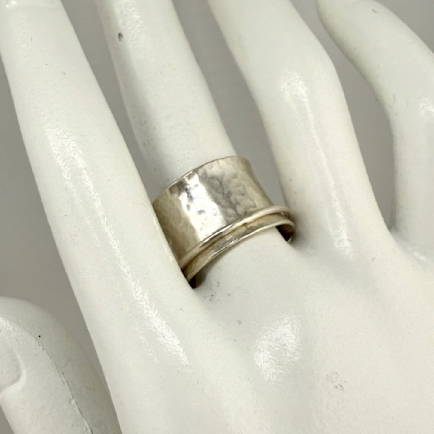 Silver spinner ring on a white marble hand display