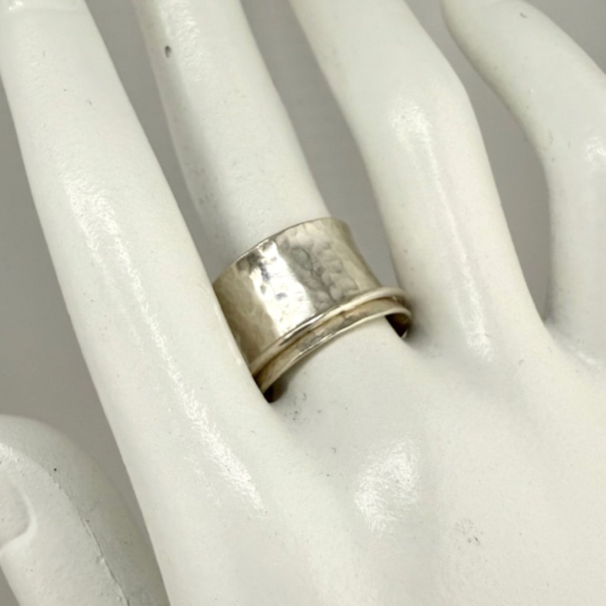 Silver spinner ring on a white marble hand display