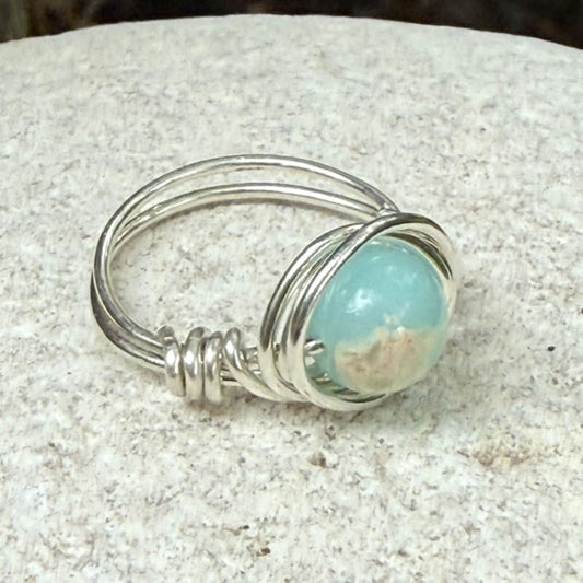 Silver ring with a aqua sea sediment jasper gemstone on a stone surface