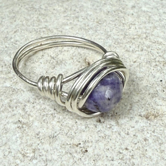 Silver wire-wrapped ring with a lapis lazuli gemstone on a textured surface